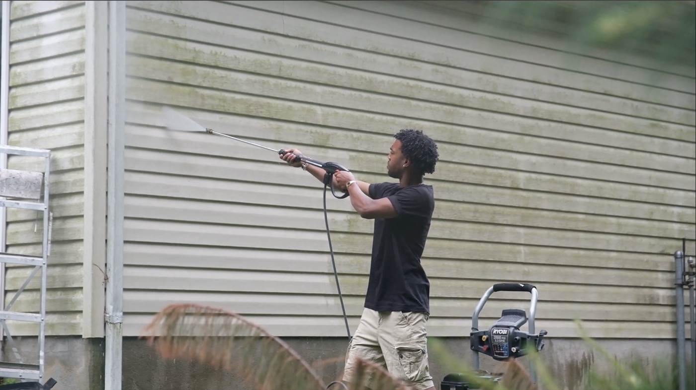 Power washing the side of a house with a pressure washer